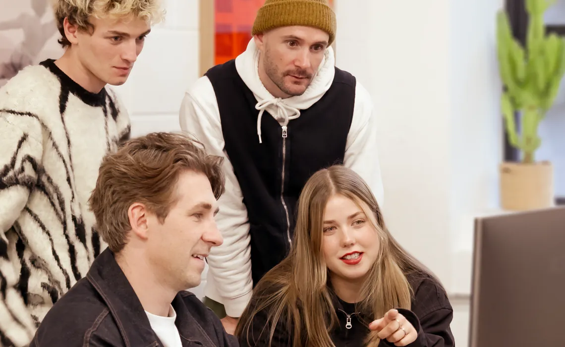 Group of people gathered around a computer