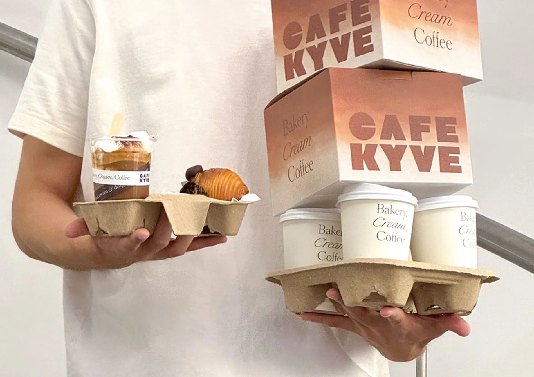 Person holding coffee cups and takeaway boxes